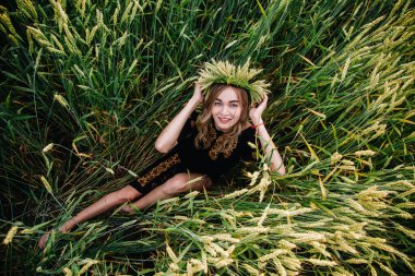 Nakış işlemiş genç, narin bir kız tarladaki buğday başaklarında yatıyor.