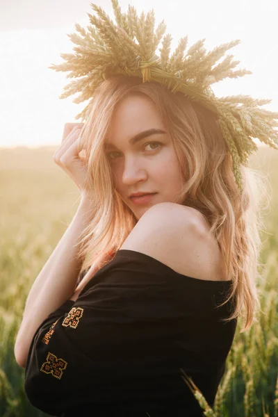 Молода струнка дівчина в вінку з пшеничних вух на заході сонця в полі — стокове фото