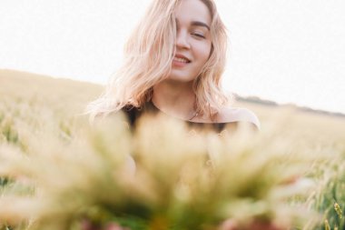 Gün batımında büyük bir buğday tarlasında işlemeli genç, narin bir kız.