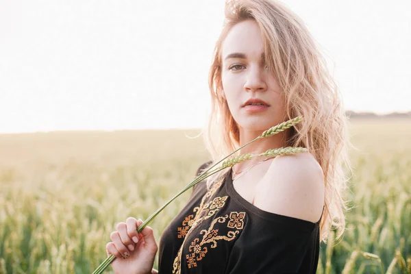 Молода струнка дівчина вишивала сукню у великому пшеничному полі на заході сонця — стокове фото