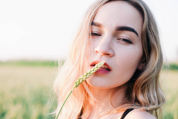 Young, slender girl embroidered dress in a large wheat field at sunset