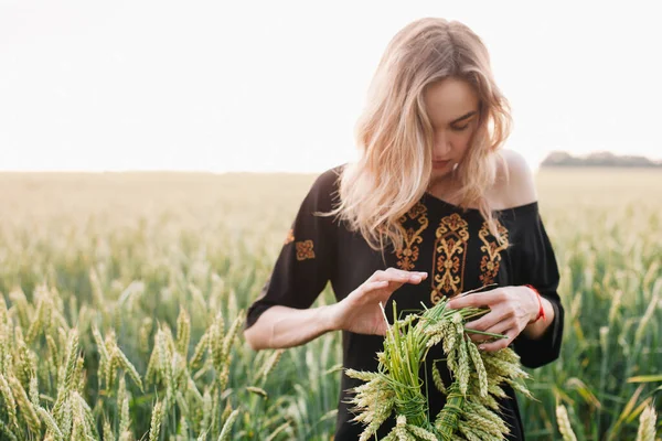 Giovane, sottile ragazza abito ricamato in un grande campo di grano al tramonto — Foto Stock