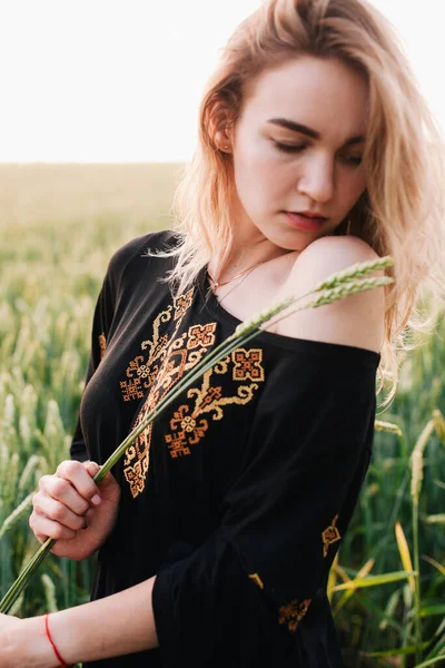 Ung, smal flicka broderad klänning i ett stort vetefält vid solnedgången — Stockfoto