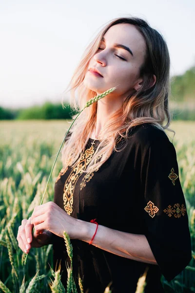 Ung, smal flicka broderad klänning i ett stort vetefält vid solnedgången — Stockfoto