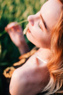 Gün batımında büyük bir buğday tarlasında işlemeli genç, narin bir kız.