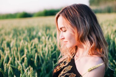 Gün batımında büyük bir buğday tarlasında işlemeli genç, narin bir kız.