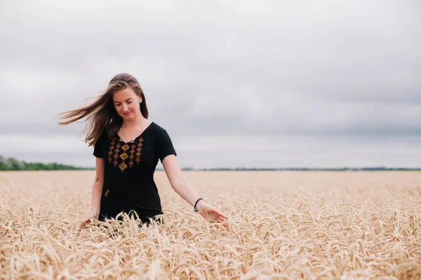 Menina bonita, esbelta em um campo de trigo contra o céu de chuva — Fotografia de Stock