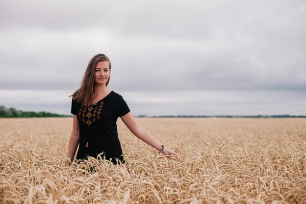 Hermosa, chica delgada en un campo de trigo contra el cielo lluvioso —  Fotos de Stock