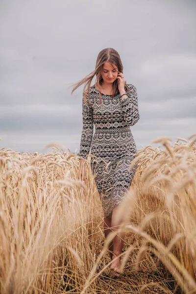 Όμορφη, λεπτή κοπέλα σε ένα χωράφι με σιτάρι ενάντια στον ουρανό της βροχής — Φωτογραφία Αρχείου