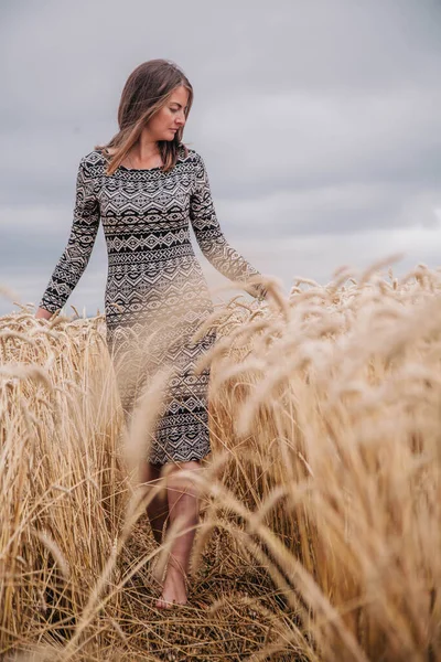 Vacker, smal flicka på ett vetefält mot regnskyn — Stockfoto