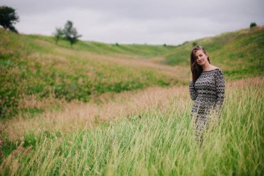 Üzerinde kır çiçekleri olan çayırlık bir elbise içinde güzel, ince bir kız.