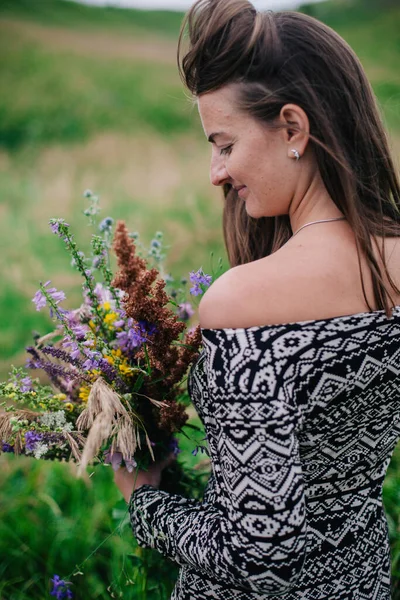 Vacker, smal flicka i en äng klänning med vilda blommor — Stockfoto