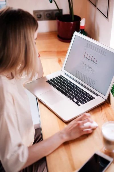 Genç bir kız bir kafede dizüstü bilgisayarda çalışıyor ve cappuccino içiyor.. 