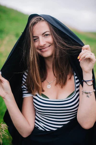 Beautiful girl in a black long skirt and striped T-shirt walks in green hole — Stock Photo, Image