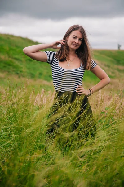 Belle fille en jupe longue noire et T-shirt rayé marche dans le trou vert — Photo