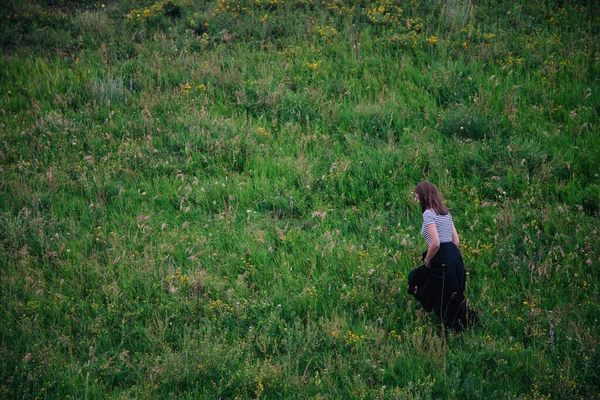 Krásná dívka v černé dlouhé sukni a pruhované tričko chodí v zelené díře — Stock fotografie
