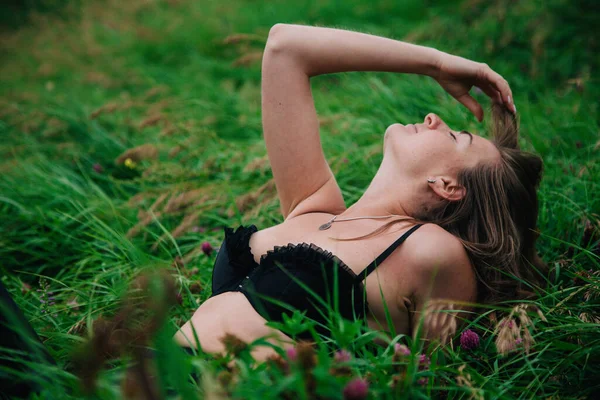 Красивая девушка в черном лифчике и длинной юбке лежит в траве — стоковое фото
