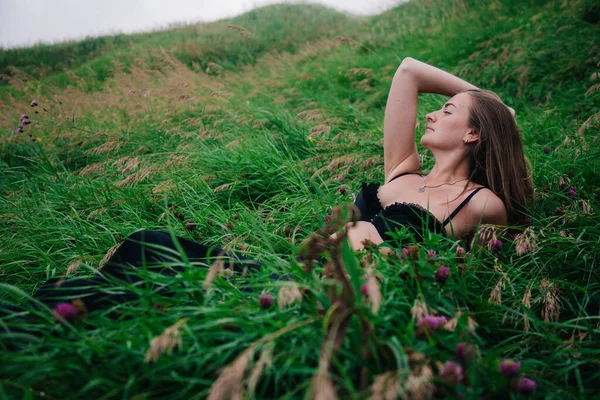검은 브라와 긴 치마를 입은 아름다운 소녀가 풀밭에 누워 있다 — 스톡 사진