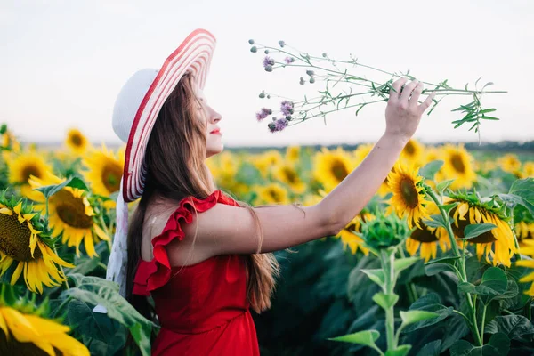 Une jeune fille mince dans une robe rouge pose dans un champ de tournesols — Photo