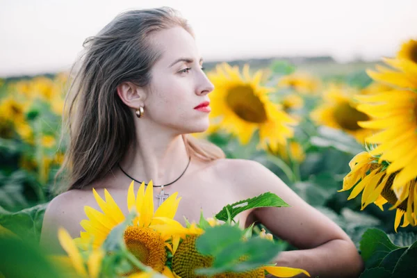 Chica joven y delgada sin ropa está cubierta de girasoles — Foto de Stock