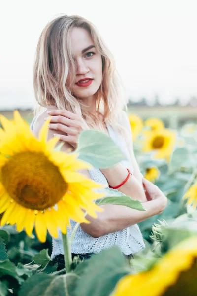 Jeune fille mince dans un T-shirt blanc pose au coucher du soleil dans un champ de tournesols — Photo