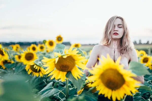 Junges, schlankes Mädchen oben ohne posiert bei Sonnenuntergang in einem Sonnenblumenfeld — Stockfoto