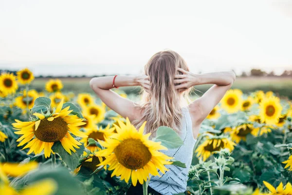 Młoda, szczupła dziewczyna w białej koszulce pozuje o zachodzie słońca na polu słoneczników — Zdjęcie stockowe