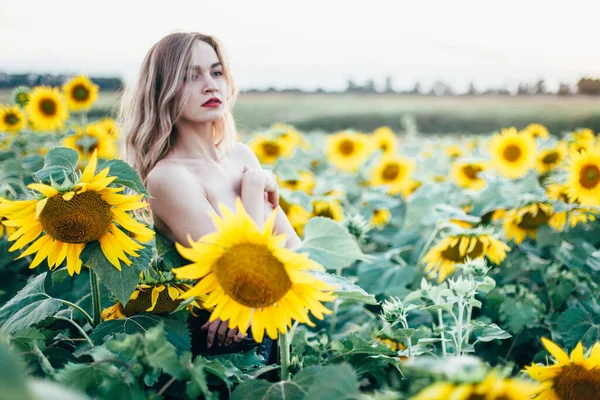 Giovane, sottile ragazza in topless posa al tramonto in un campo di girasoli — Foto Stock