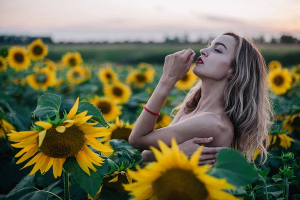 Giovane, sottile ragazza in topless posa al tramonto in un campo di girasoli — Foto Stock