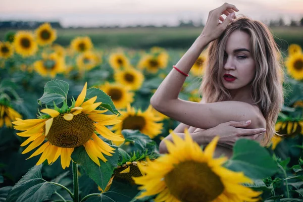 Giovane, sottile ragazza in topless posa al tramonto in un campo di girasoli — Foto Stock