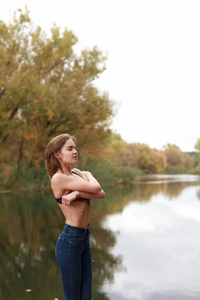 Jong, slank meisje staat tegen de achtergrond van het herfstlandschap — Stockfoto