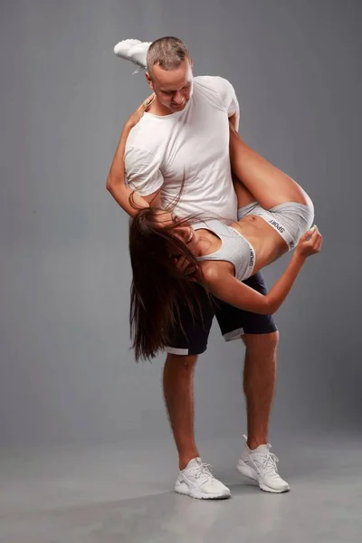 Young sports couple engaged in fitness on a gray background — Stock Photo, Image