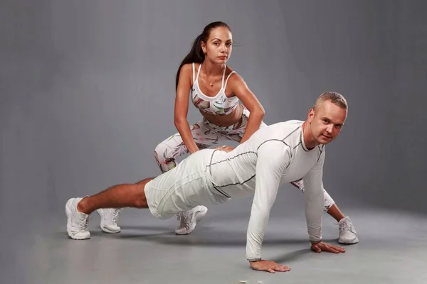 Молодая спортивная пара занимается фитнесом на сером фоне — стоковое фото