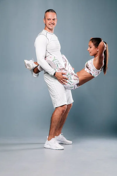 Mladý sportovní pár zapojený do fitness na šedém pozadí — Stock fotografie
