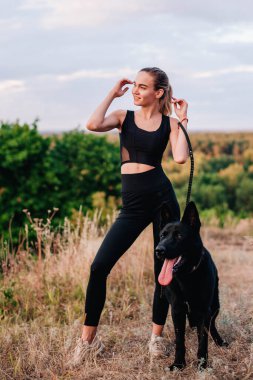 Gün batımında genç ve narin bir kız çoban köpeğiyle oynuyor.