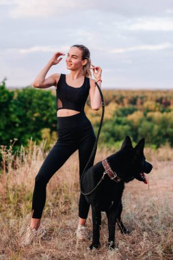 Gün batımında genç ve narin bir kız çoban köpeğiyle oynuyor.