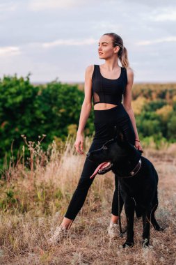 Gün batımında genç ve narin bir kız çoban köpeğiyle oynuyor.