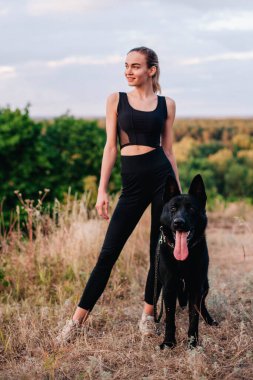 Gün batımında genç ve narin bir kız çoban köpeğiyle oynuyor.