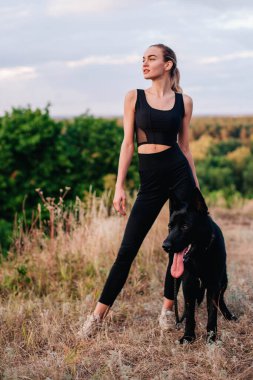 Gün batımında genç ve narin bir kız çoban köpeğiyle oynuyor.