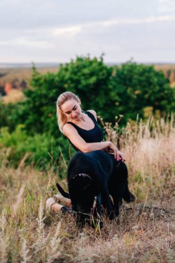 Gün batımında genç ve narin bir kız çoban köpeğiyle oynuyor.