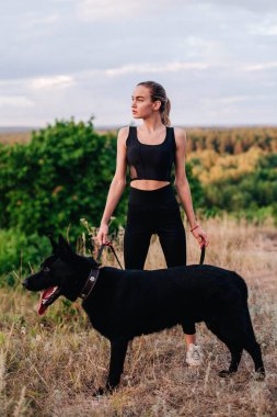 Gün batımında genç ve narin bir kız çoban köpeğiyle oynuyor.