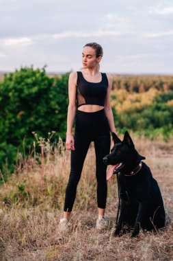 Gün batımında genç ve narin bir kız çoban köpeğiyle oynuyor.