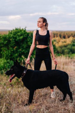 Gün batımında genç ve narin bir kız çoban köpeğiyle oynuyor.