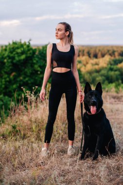 Gün batımında genç ve narin bir kız çoban köpeğiyle oynuyor.