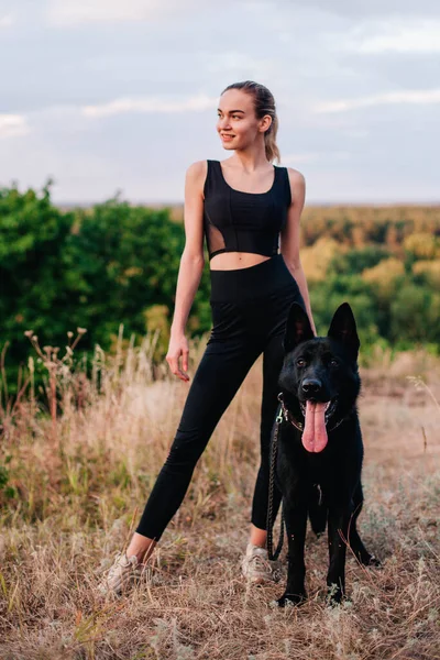 Gün batımında genç ve narin bir kız çoban köpeğiyle oynuyor.