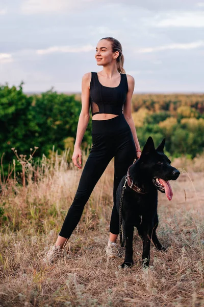 Gün batımında genç ve narin bir kız çoban köpeğiyle oynuyor.