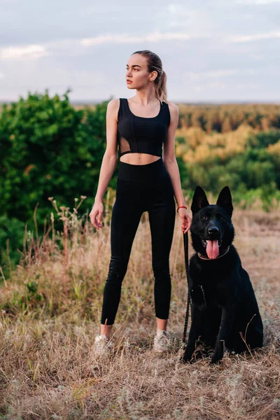 Gün batımında genç ve narin bir kız çoban köpeğiyle oynuyor.