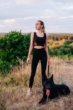 Gün batımında genç ve narin bir kız çoban köpeğiyle oynuyor.