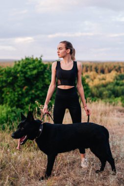 Gün batımında genç ve narin bir kız çoban köpeğiyle oynuyor.