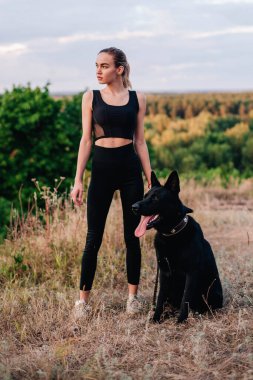 Gün batımında genç ve narin bir kız çoban köpeğiyle oynuyor.